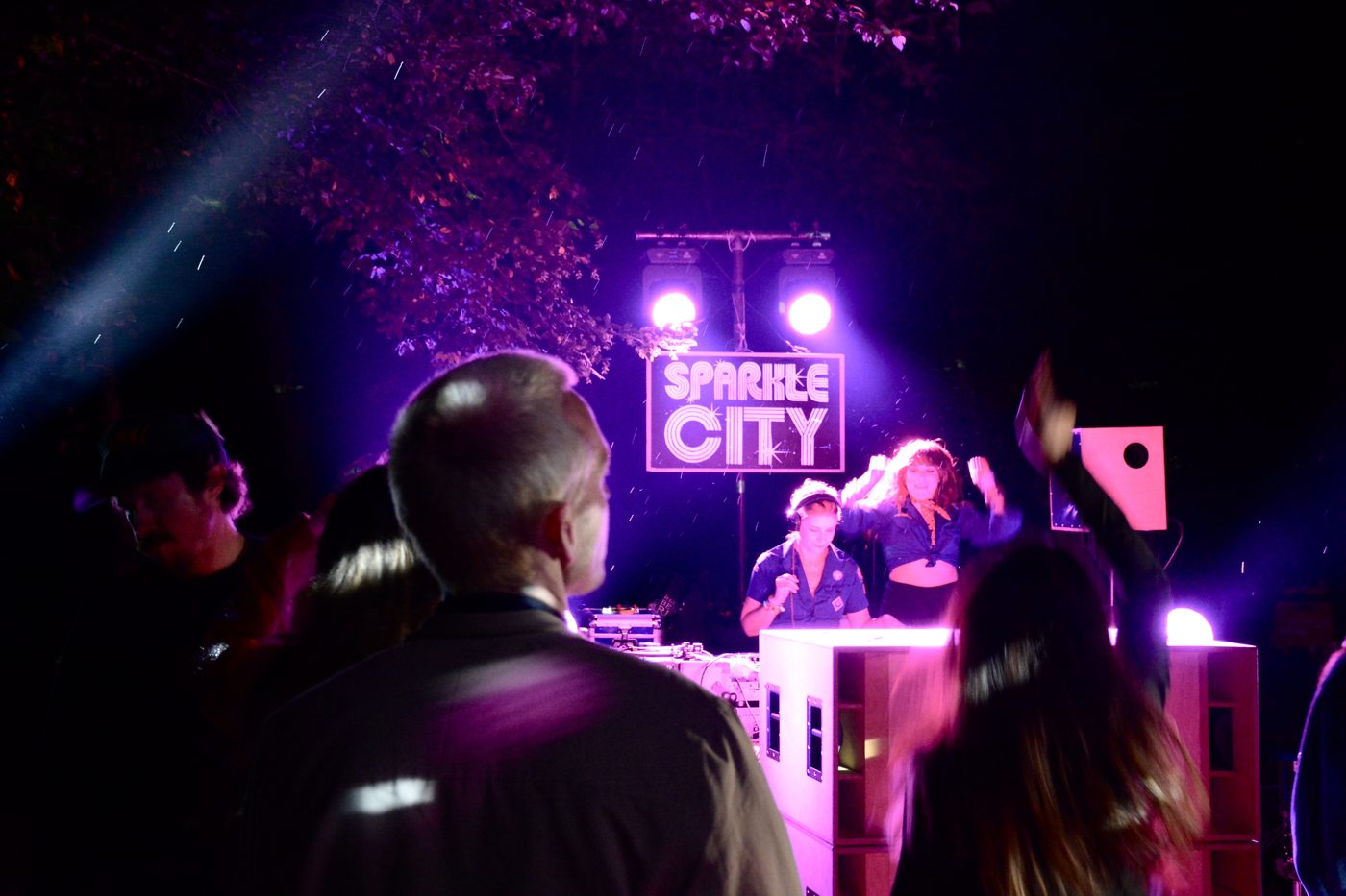 The DJ booth at night under the lit Sparkle City sign
